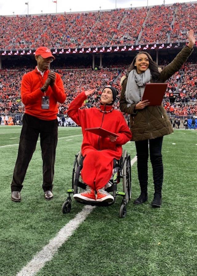 2020 President's Prize winners Jen Schlegel and Simone Bacon waive to the crowd from the field during halftime of the Penn. State game (11/23/19) as President Drake joins in the crowd’s applause.