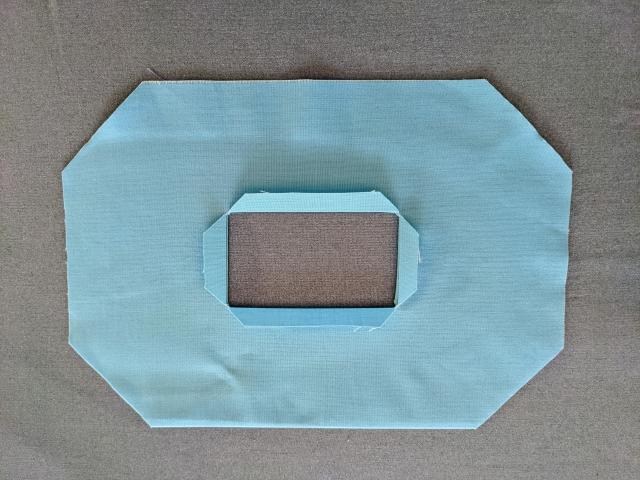 blue fabric mask with tabs folded back and pressed to create large size center square.
