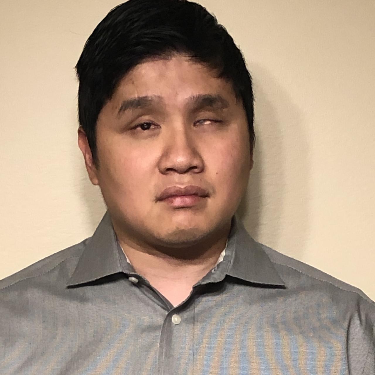 Head shot of Pete Bossley, who has short black hair and is wearing a grey collared shirt
